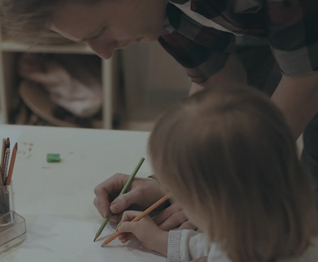 A tutor and child drawing with coloured pencils