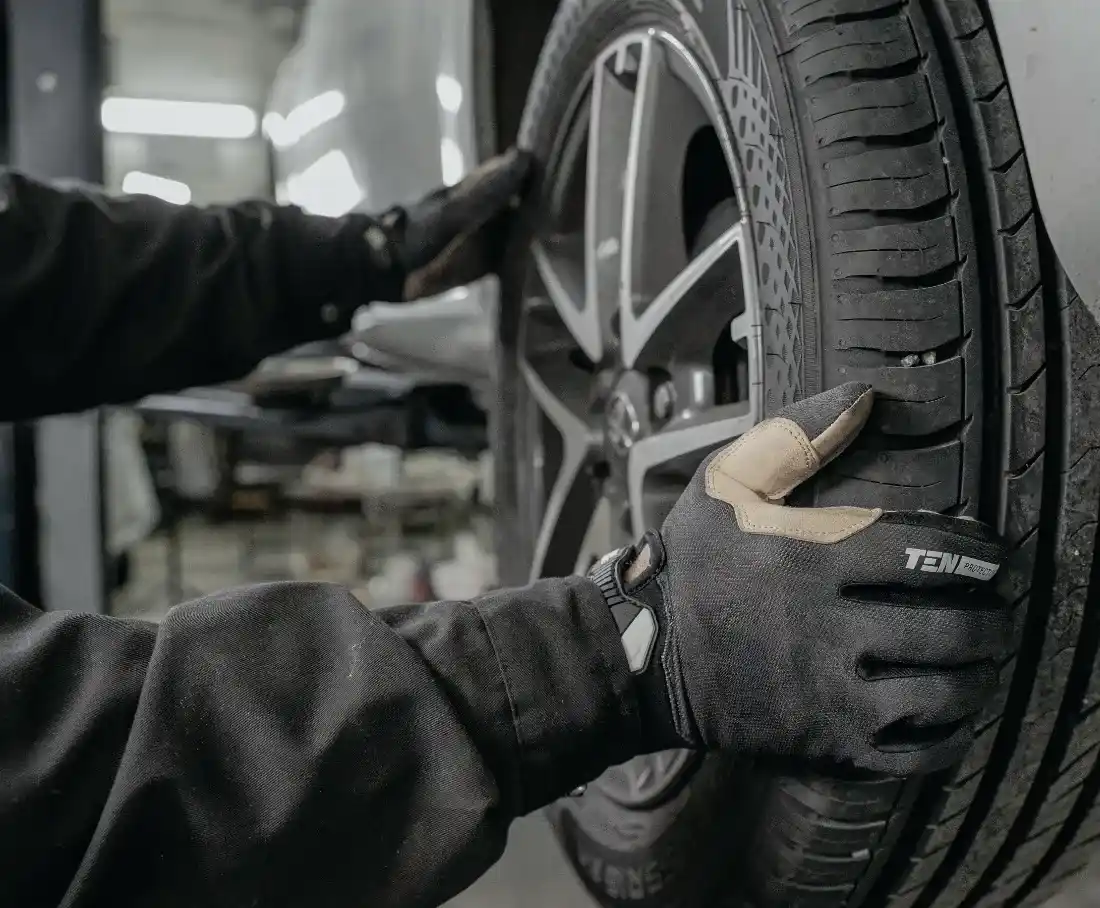Gloved hands checking a wheel in a garage